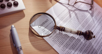 Magnifying glass examining and signing a legal contract document